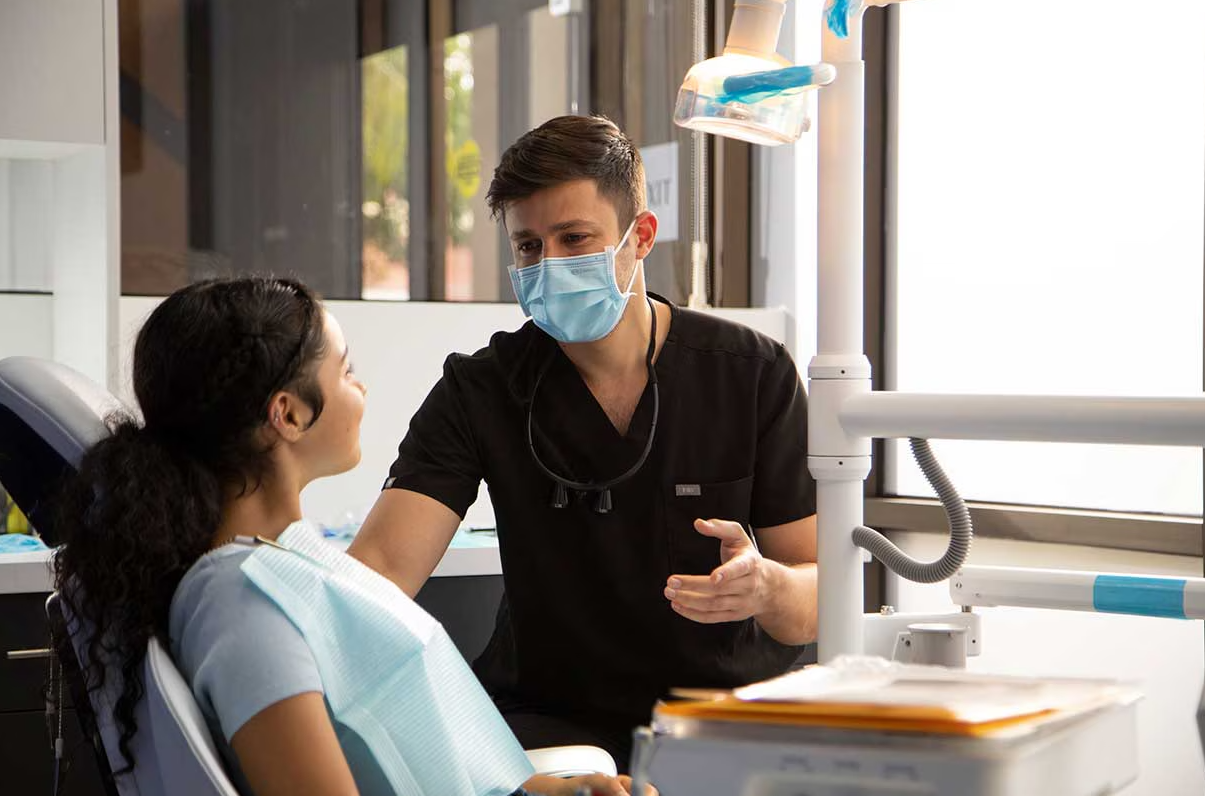 Woman in a dental chair speaking with a male dentist